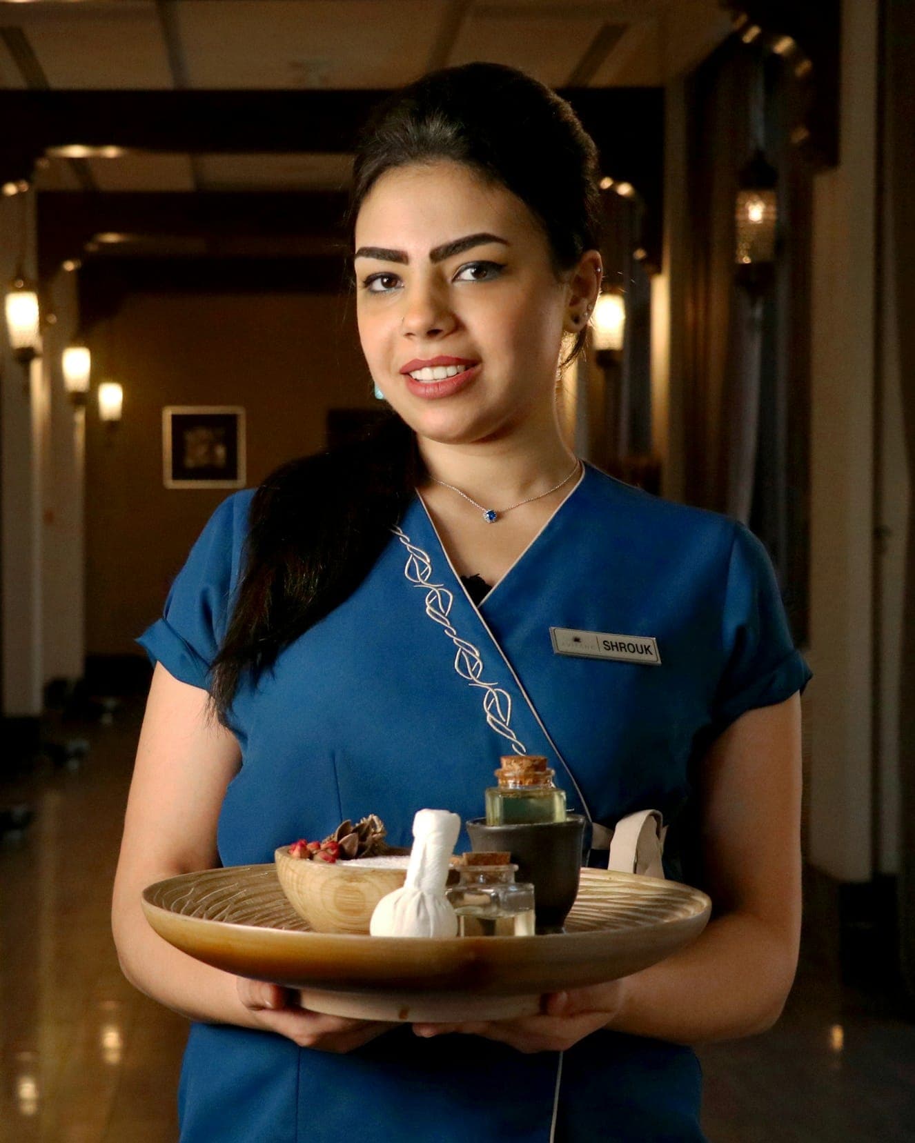 A smiling hotel colleague in uniform in a calm corridor