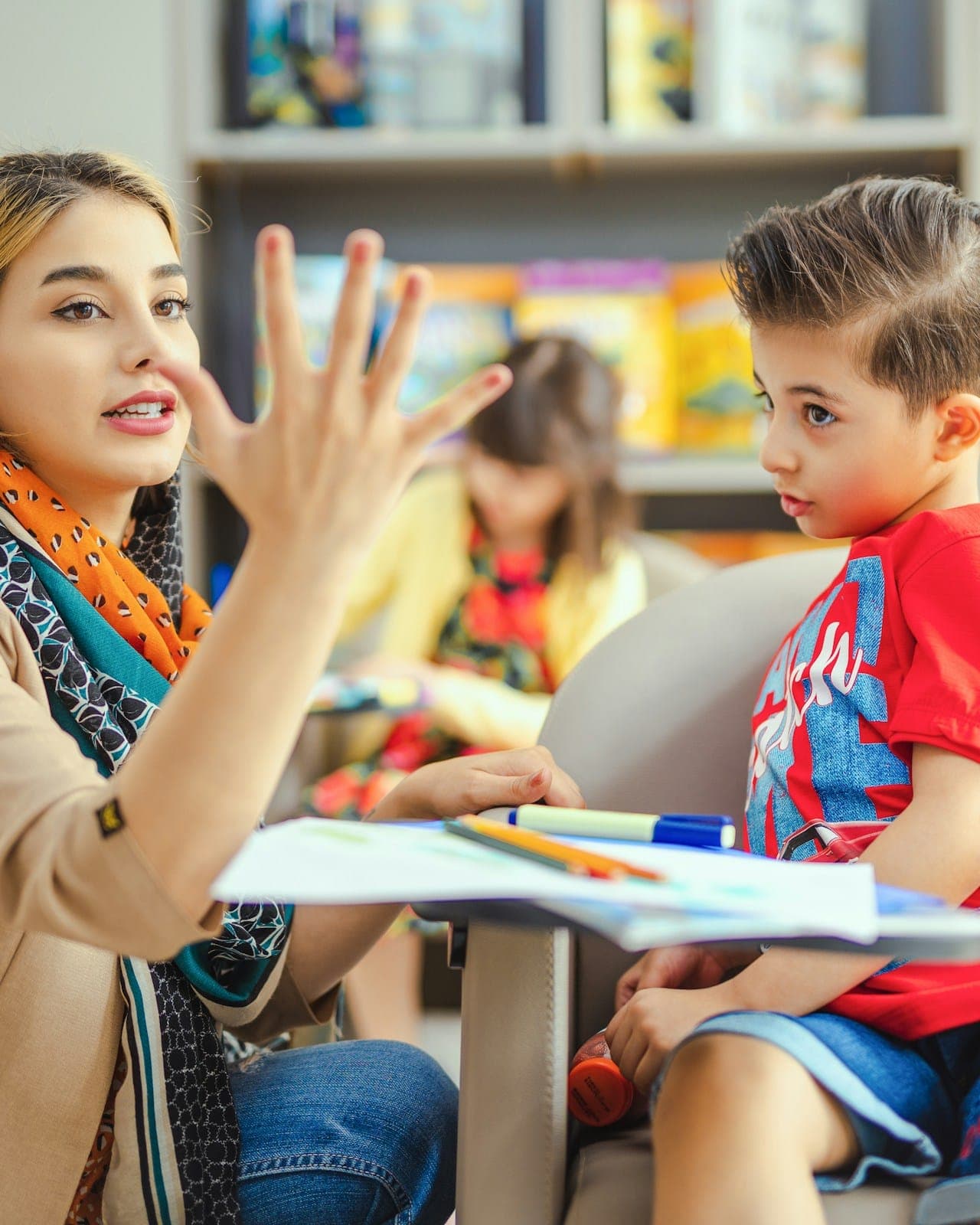 A professional helps a young boy practise counting at a table