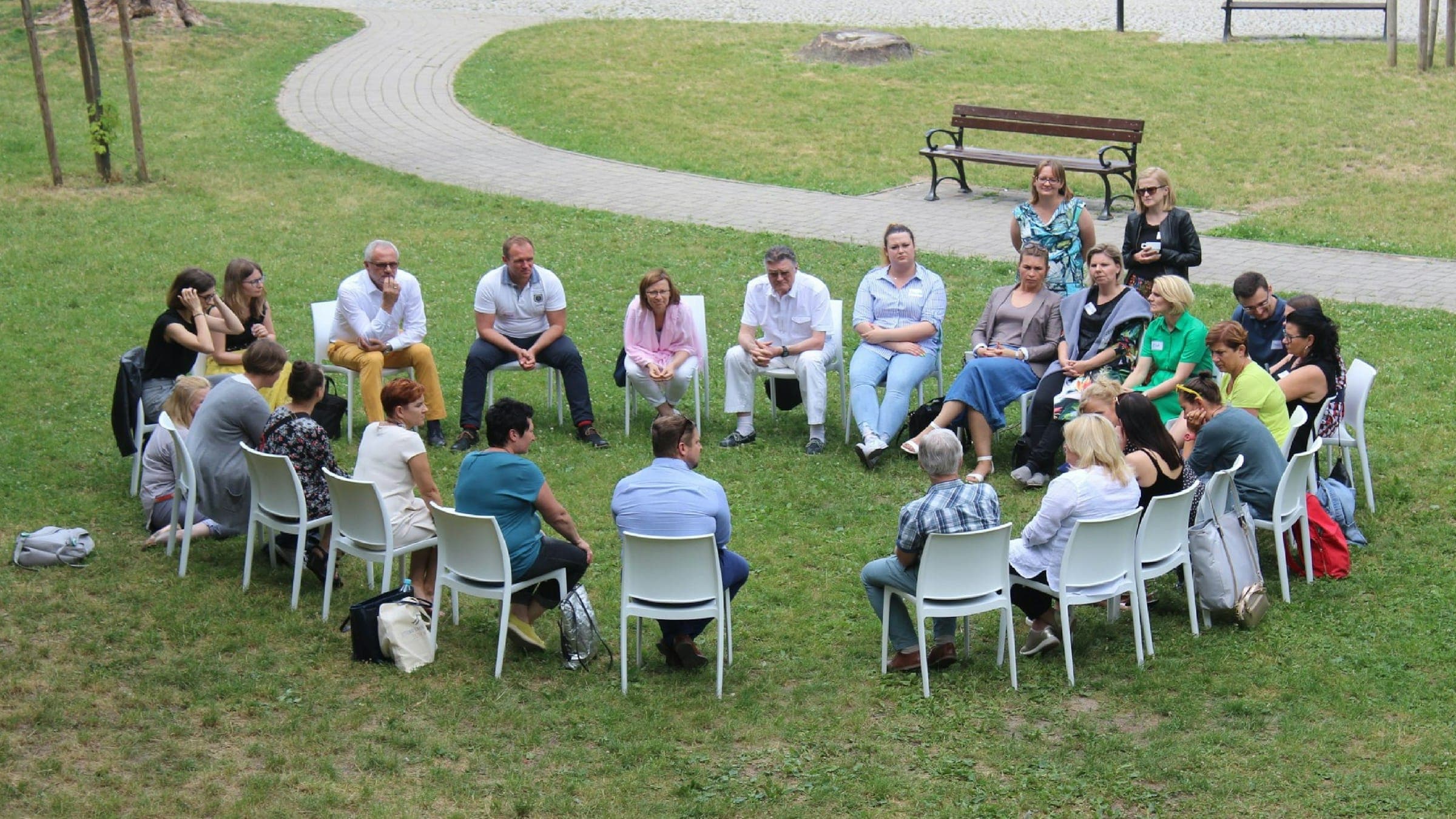 A team sits in a circle of chairs on a lawn