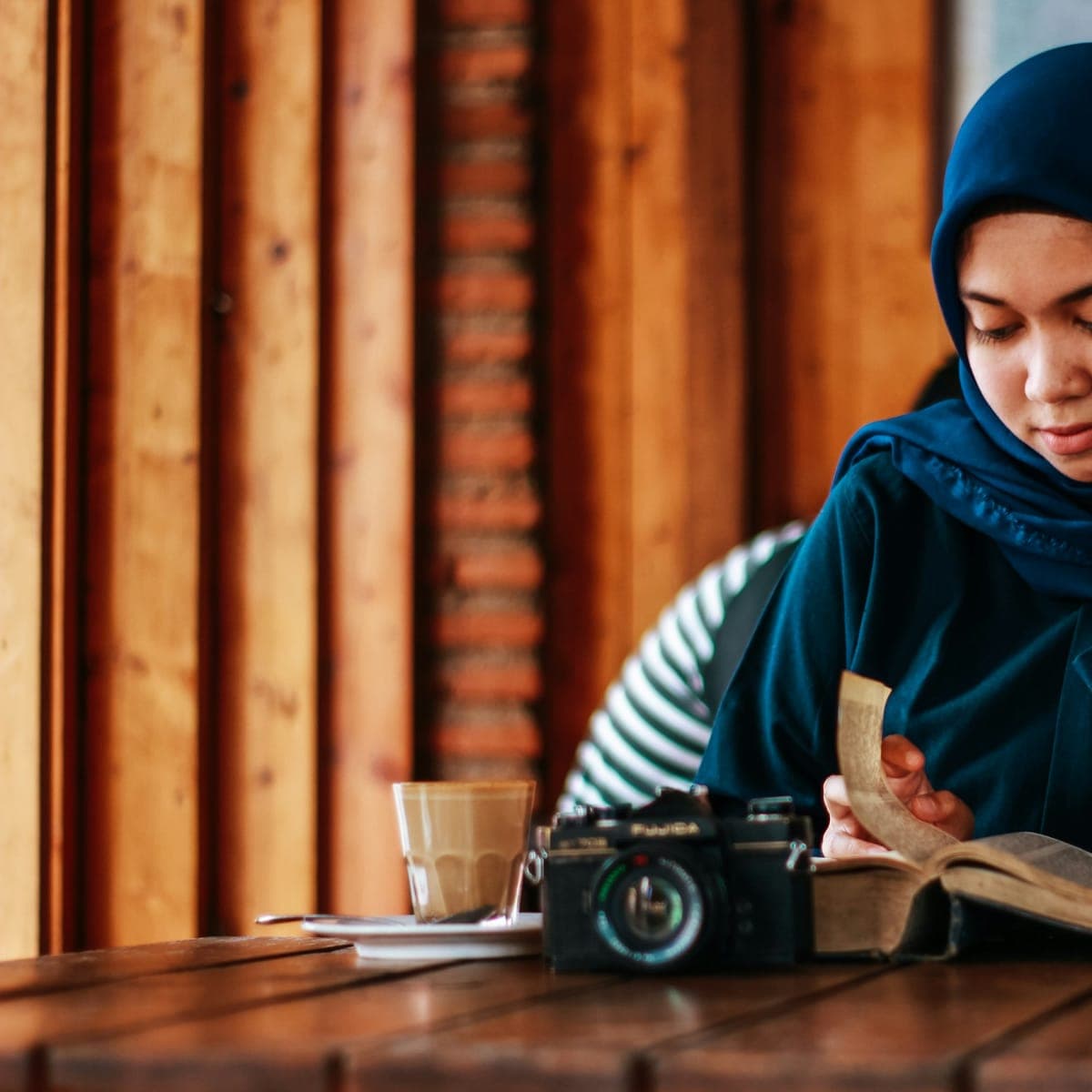 A woman reads thoughtfully at a wooden table