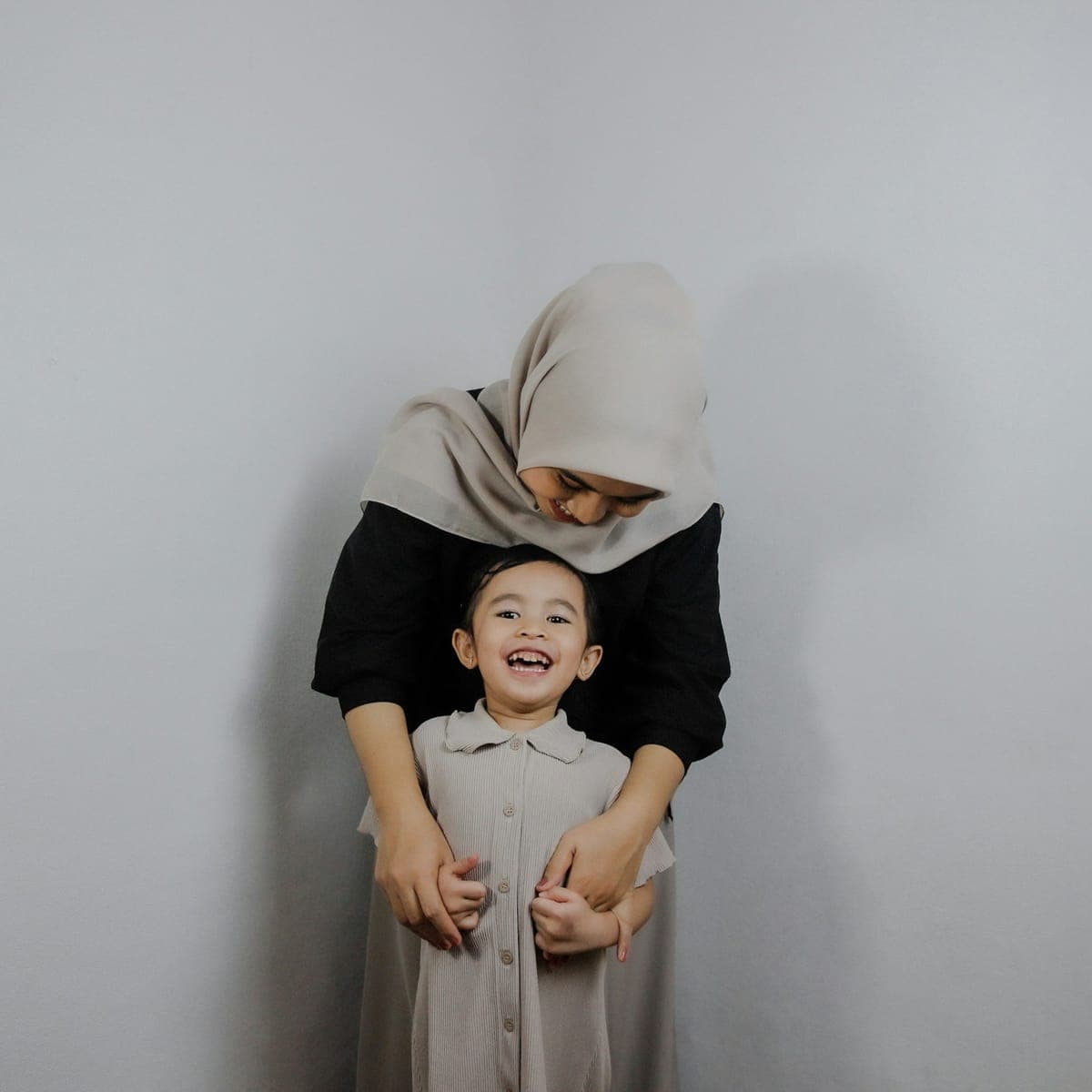 A laughing child with her mother standing behind her