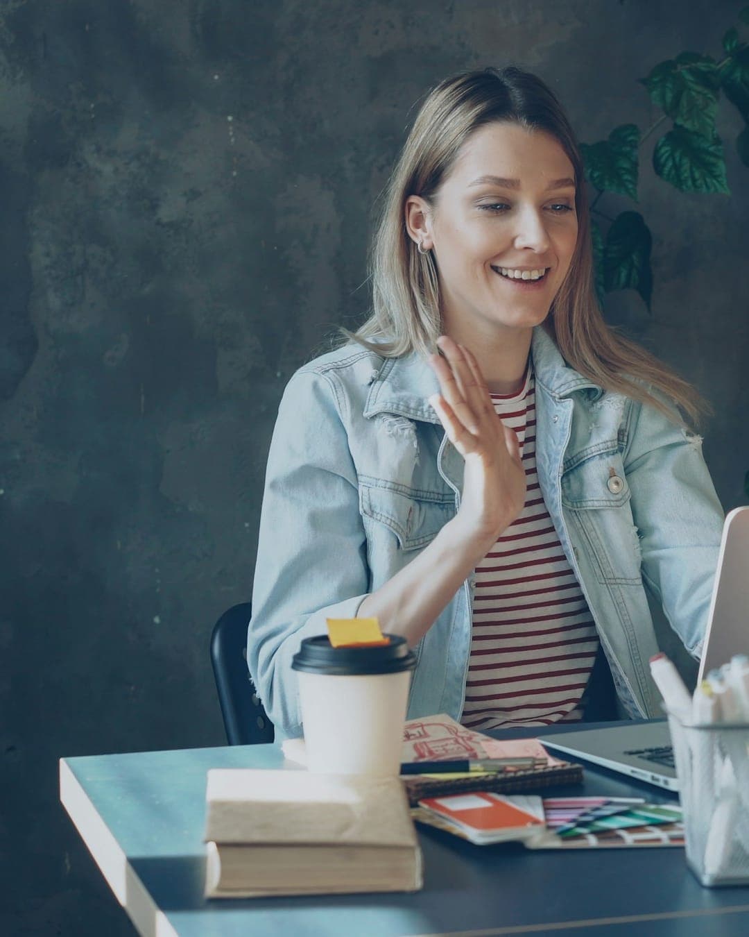 A woman waves hello at the start of an online video conversation